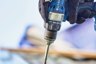 a person using a drill to drill a piece of wood