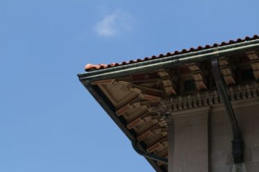 Corner of a building with tiled roof against blue sky