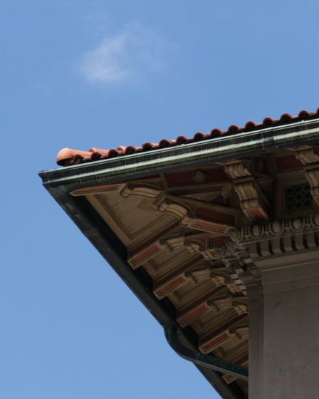 Corner of a building with tiled roof against blue sky